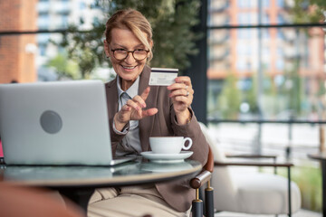 Mature woman enjoying online shopping with credit card and laptop