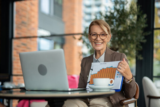 Smiling mature businesswoman presenting sales growth business chart