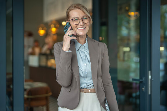Confident senior woman talking on smartphone in urban setting - Powered by Adobe