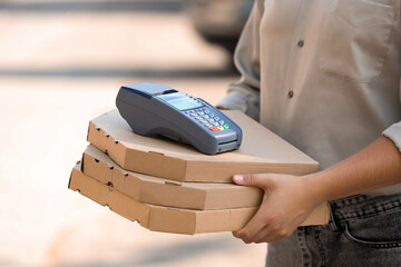 Male courier with pizza boxes and payment terminal on street, closeup