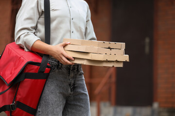 Male courier with pizza boxes and food bag on street