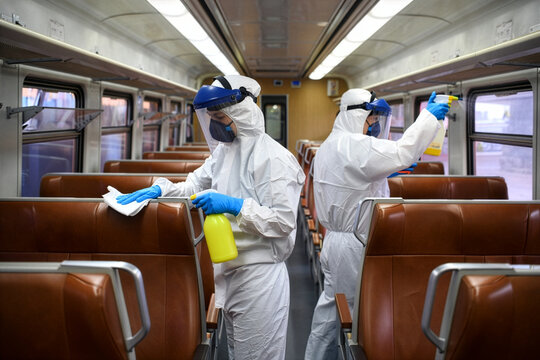 Workers in protective suits disinfect train interior, ensuring public safety and hygiene