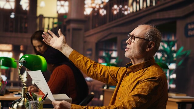 Elderly actor in a library focusing on script reading and memorization, preparing for a classic drama play with dedication and passion for theatre performance. Dramatic arts.