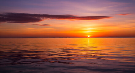 Intense orange and purple sunset over a calm ocean horizon