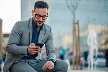 Businessman using smartphone in urban setting during break time