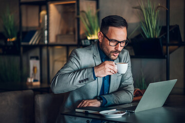 Businessman drinking coffee and working on laptop in cafe