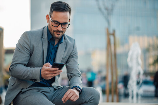 Businessman using smartphone in urban setting during break time
