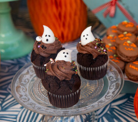 Chocolate cupcakes decorated with white frosted ghosts for Halloween. Festive cupcakes