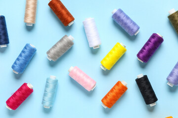 Set of colorful thread spools on blue background