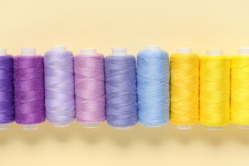 Row of colorful thread spools on beige background