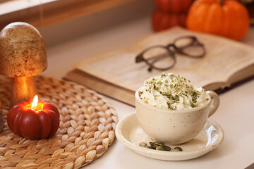 Cup of pumpkin latte on desk in room, closeup