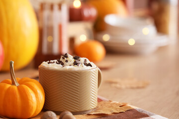 Cup of latte with pumpkin and autumn leaf on table, closeup