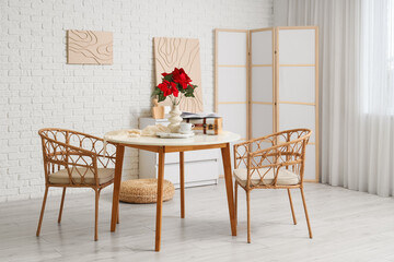 Interior of room with Christmas plant poinsettia on dining table and folding screen