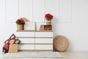 Interior of light room with Christmas plant poinsettia on commode