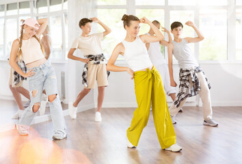 Naklejka premium Active teenagers practicing hip-hop dance in training hall during group dancing classes