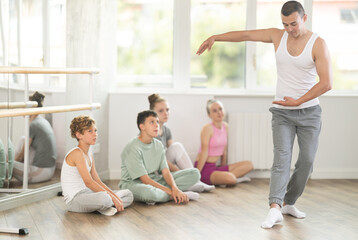 During rehearsal, teenagers children look at man teacher, study performance of dance, memorize movements. Master class from experienced coach and teacher