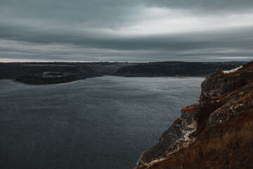 Scenic view of Bakota Bay in Ukraine with rocky cliffs, calm river, and dramatic cloudy sky. Beautiful nature landscape, travel and adventure destination.