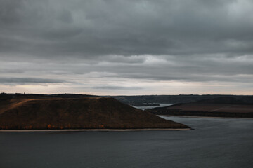 Scenic view of Bakota Bay in Ukraine with rocky cliffs, calm river, and dramatic cloudy sky. Beautiful nature landscape, travel and adventure destination.