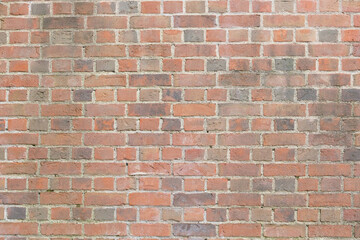 Textured brick wall featuring a mix of red and gray bricks, showcasing the rustic charm and character of traditional masonry in a warm, inviting atmosphere