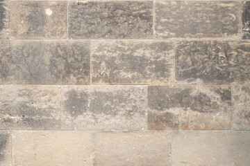 Textured stone wall featuring a blend of gray and beige tones, showcasing natural patterns and variations, ideal for backgrounds and architectural design concepts