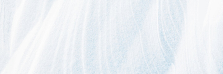 Wide panoramic winter background with snowy ground. Natural snow texture. Wind sculpted patterns on snow surface.