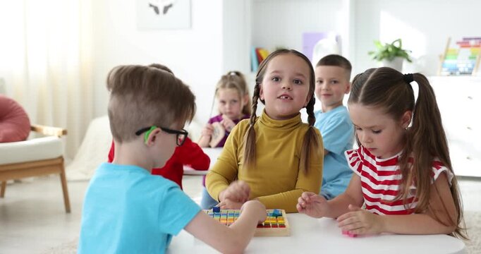 Cute children at white table during lesson in elementary school