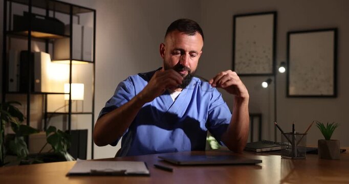Tired doctor working on laptop at table in clinic during night shift