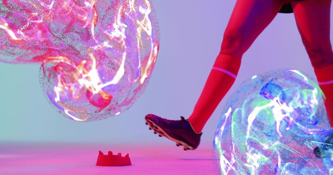 Extending female athlete's leg in red socks, cleated shoe toward glowing orbs in studio, red marker