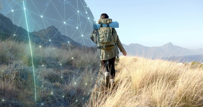 Hiking hiker carrying backpack with rolled mat through coastal grasses, with digital overlay