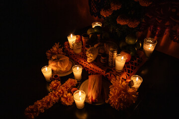 Ofrenda tradicional de Día de Muertos con velas, pan de muerto, flores de cempasúchil, papel...