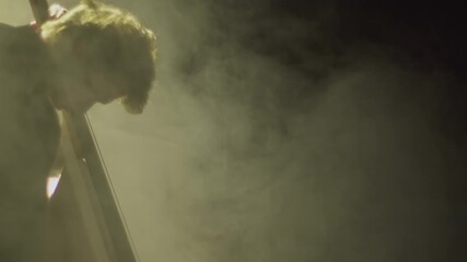 Musician plays bass contrabass bow in smoky venue during live performance