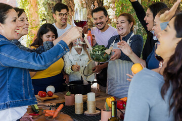 Group of Latin American Adult Students With Teacher Preparing recipe ingredients in Cookery Class in Mexico. Hispanic people multi generations learning together to cook in a terrace outdoors
