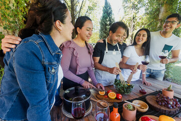 Group of Latin American Adult Students With Teacher Preparing recipe ingredients in Cookery Class in Mexico. Hispanic people multi generations learning together to cook in a terrace outdoors