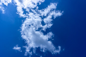 bright blue sky with white, fluffy clouds. The scene depicts a clear, sunny day, with the sun...