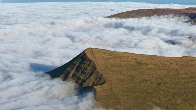 Dramatic mountain landscape showing Cribyn peak emerging from a sea of clouds