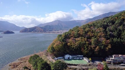 Aerial landscape of Lake Kawaguchi in Japan surrounded by autumn-colored trees and mountains.