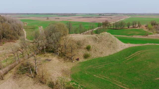 Historic Latvian Dobes hillfort emerges, spring landscape symbolizing endurance