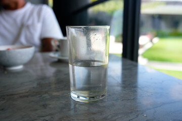 A glass of half-filled mineral water on a marble dining table, mineral water filled in glass cups, healthy culture by drinking mineral water regularly