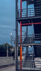 Construction site in the city.Modern fire escape staircase with red steel columns and railings, industrial metal structure in urban architecture, safety design