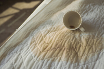 Coffee stain on a bed in bright morning light