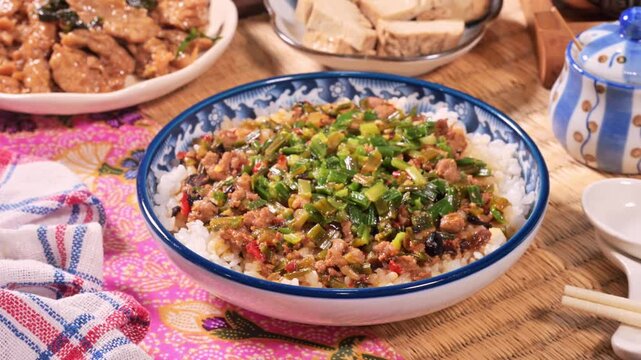 Fried minced pork with chive flower and black bean sauce over rice on wood table