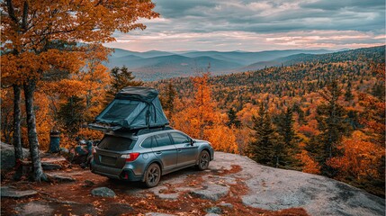 A scenic view of autumn foliage with a parked car featuring a rooftop tent, set against a backdrop of mountains and a cloudy sky.