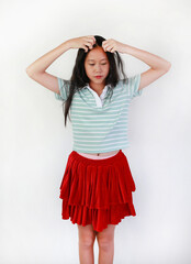 Portrait of Asian girl in beautiful outfit is styling her hair, Child arranging her hair with her...