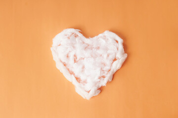 Heart-shaped cotton is placed against an orange background