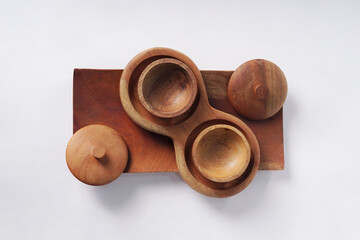 The wooden cup, complete with its lid, rests on a wooden dish over a clean white surface