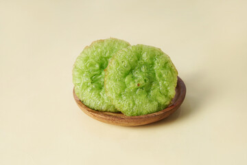 A traditional cucur cake is placed on a wooden plate against a cream background
