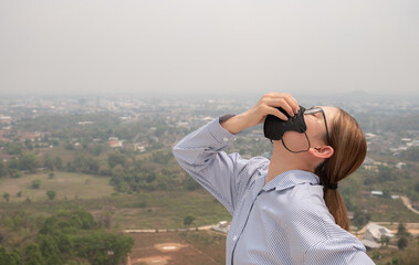 Asian businesswoman wearing N95 mask for protect Bad air pollution (PM2.5) covered Chiang Rai province, Thailand. PM2.5 levels meaning the air quality posed a health hazard.