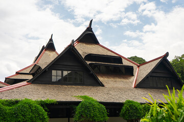 The iconic architecture of the ITB Auditorium in Bandung, a colonial-era heritage building. Its distinctive roof blends beautifully with lush, green climbing plants.