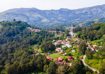 A stunning aerial view of Maubisse village in the highlands of Ainaro, Timor-Leste. Houses are scattered across the ridges and valleys, surrounded by a vast, green mountain landscape