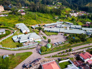 An aerial view of a public building complex, in the mountain town of Maubisse, Ainaro, Timor-Leste. The facility is set amidst a lush green highland landscape.